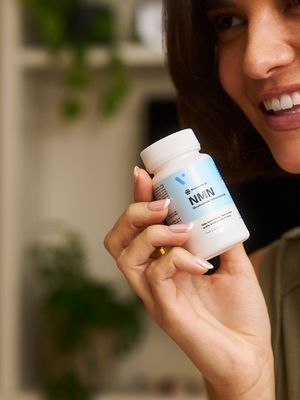 A woman smiling with a bottle of vivanmn NMN